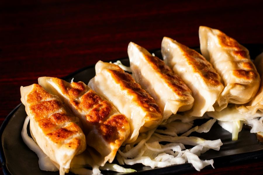 黒い皿に並べた焼き目のついた焼き餃子